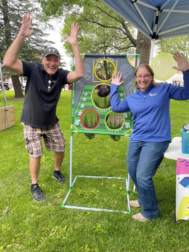 Randy and coworker Deana Hanson posing in front of a carnival game.